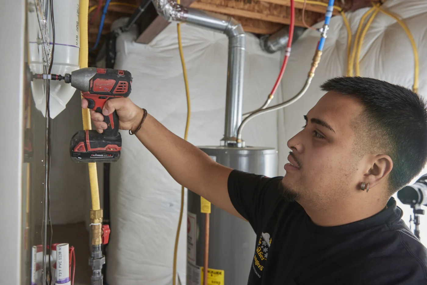 A Weather Changers technician working on a furnace in a Denver basement