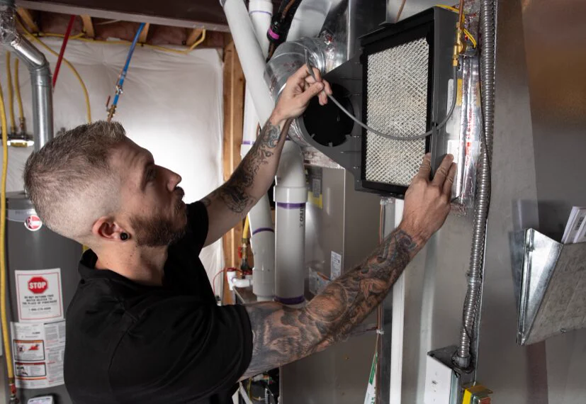 A technician fitting a whole-home air filter and humidifier